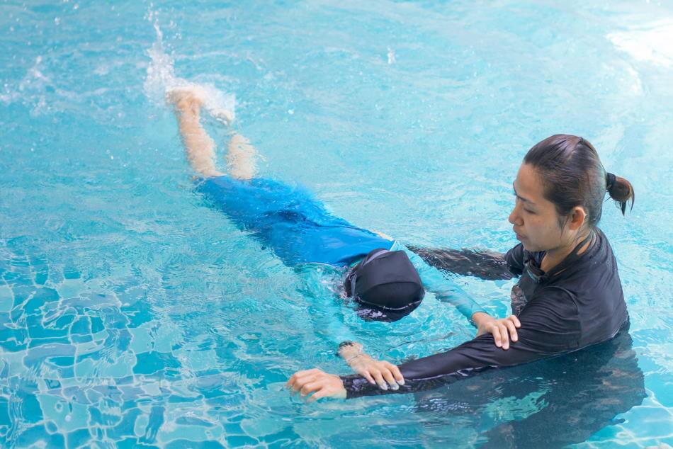 Swim coach teaching child to swim